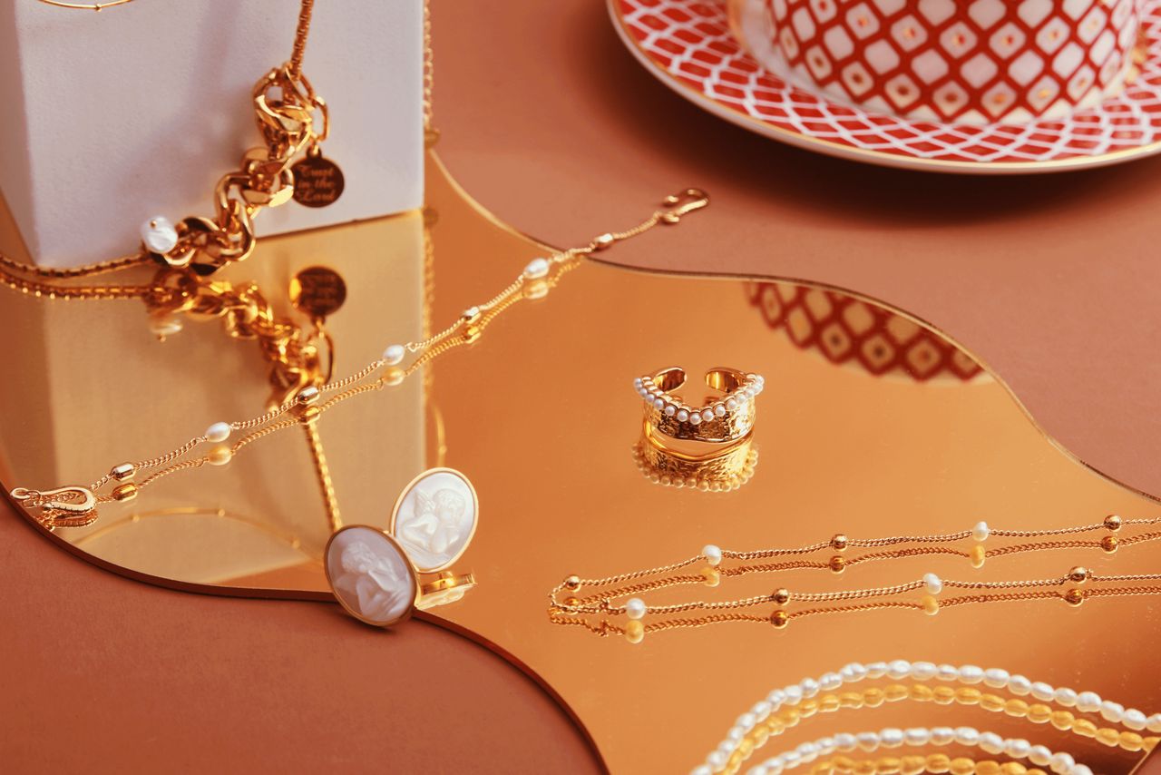 Services Stylish jewelry set elegantly displayed on a reflective gold tray with chic tableware.