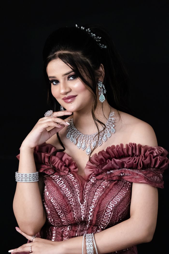 Portrait of a woman in a pink gown wearing elegant jewelry against a dark backdrop.