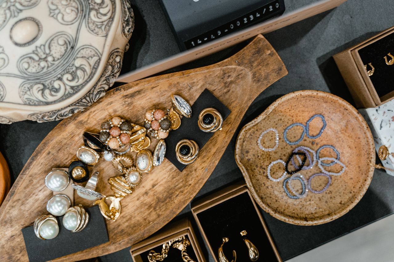 Services A top view of assorted jewelry including rings and bracelets in a wooden tray and ceramic dish.