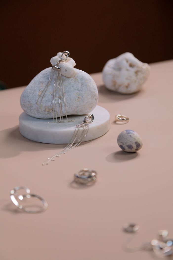 Services Close-up of elegant silver earrings on a marble stone with artistic composition.